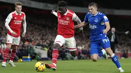 Bek Everton Vitaliy Mykolenko (kanan) berebut bola dengan gelandang Arsenal Bukayo Saka pada laga tunda pekan ke-7 Liga Inggris 2022/2023 di Emirates Stadium, Kamis (2/3/2023) dini hari WIB. Kemenangan ini membuat The Gunners kukuh di puncak klasemen Liga Inggris dengan koleksi 60 poin. (AP Photo/Kirsty Wigglesworth)