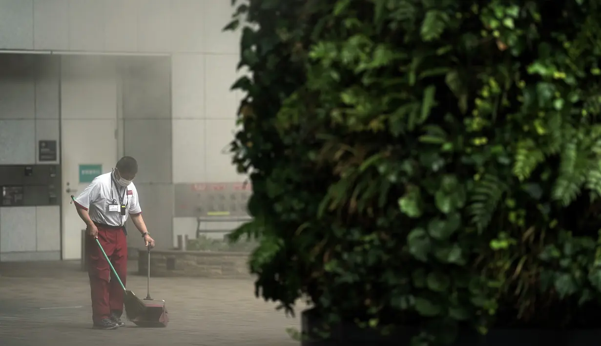 Seorang pegawai gedung yang memakai masker untuk membantu mencegah penyebaran virus corona membersihkan di dekat area kabut di Tokyo, Kamis (10/9/2020). Ibu kota Jepang itu mengonfirmasi lebih dari 270 kasus virus corona pada Kamis. (AP Photo / Eugene Hoshiko)
