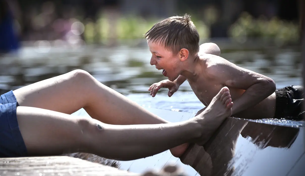 Seorang anak bermain di kolam air mancur di Taman Gorky, Moskow (7/6). Memasuki musim panas, sebagian warga Moskow menghabiskan waktu di taman untuk berjemur atau bermain air di kolam air mancur. (AFP Photo/Alexander Nemenov)