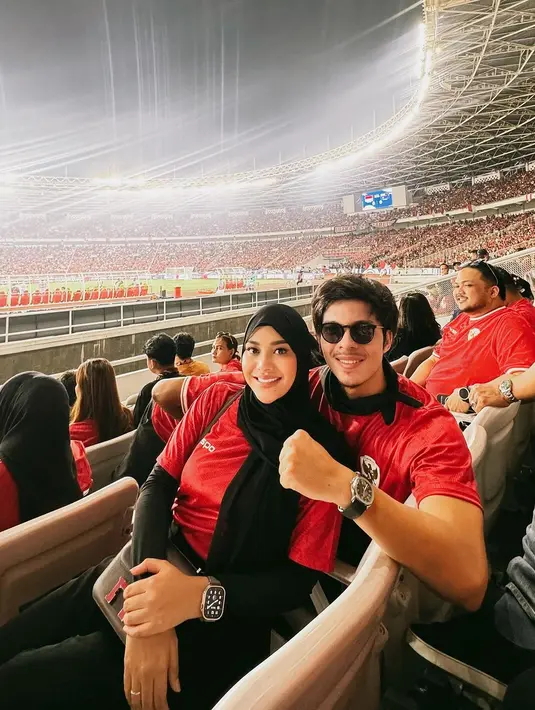 Tanpa kedua putri mereka, Aurel Hermansyah dan Atta Halilintar menikmati momen nonton pertandingan berdua dengan mengenakan jersey timnas merah yang serasi. [@aurelie.hermansyah].