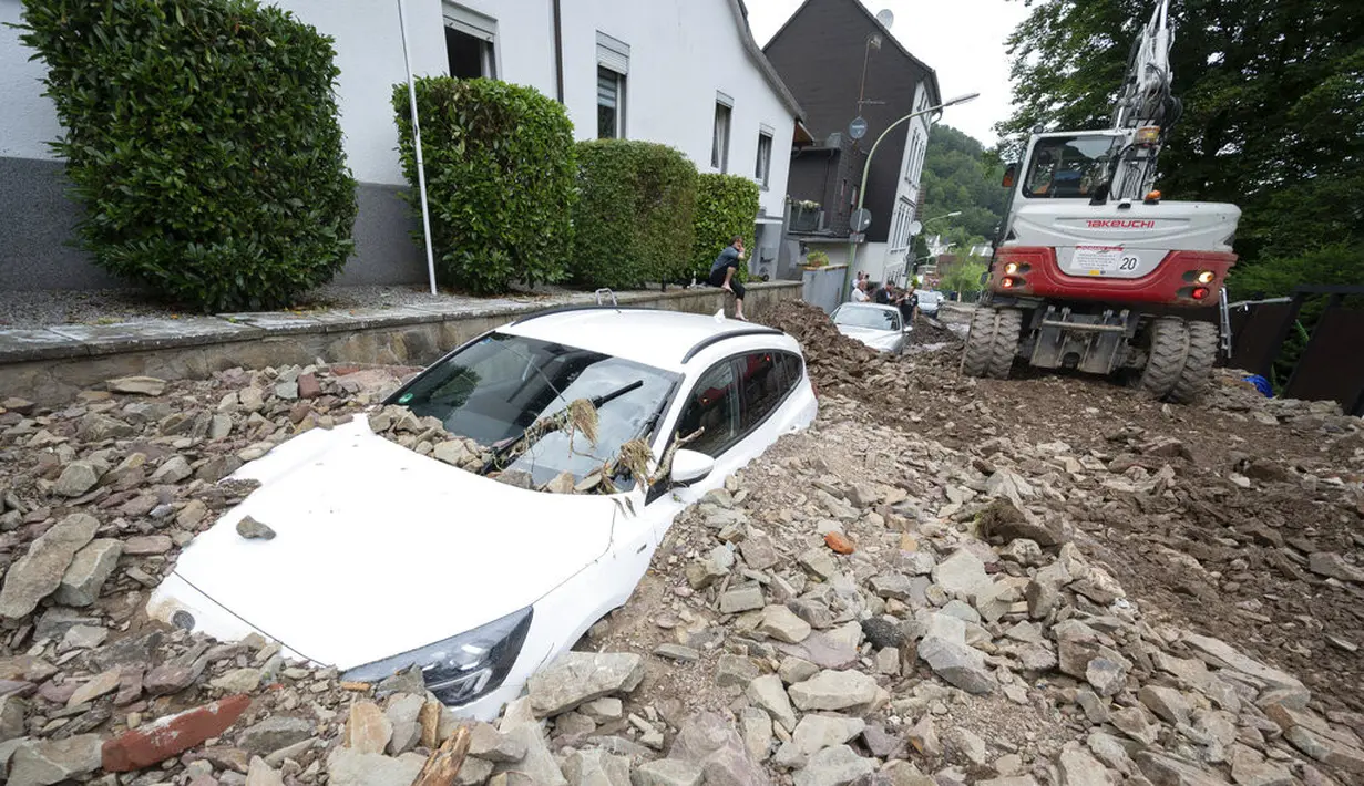 Sebuah mobil tertimbun puing-puing setelah hujan lebat menyebabkan banjir dan kerusakan besar di distrik Hohenlimburg di Hagen, Jerman, Kamis (15/7/2021). (Julian Stratenschulte/dpa via AP)
