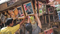 Pedagang melayani pembeli bingkai foto Presiden Jokowi dan Wakil Presiden terpilih Ma'ruf Amin yang dijualnya di Pasar Baru, Jakarta, Rabu (16/10/2019). Menjelang pelantikan presiden, foto pasangan Jokowi-Ma'ruf Amin mulaih dijual ke pasar umum. (Liputan6.com/Faizal Fanani)