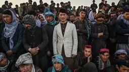 Warga Afghanistan menyaksikan peserta bergulat selama tontonan gulat mingguan yang diadakan di arena darurat di taman Chaman-e-Hozori, di Kota Kabul (12/11/2021). (AFP/Hector Retamal)