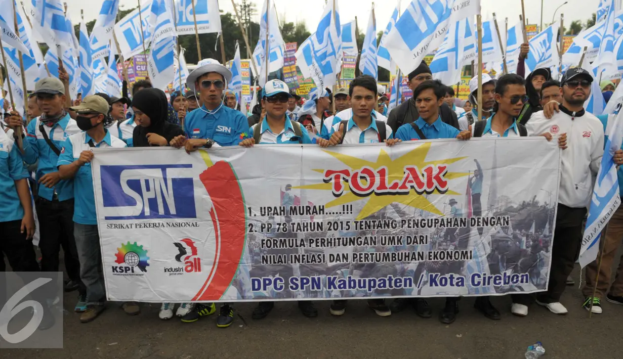Buruh membawa spanduk saat menggelar aksi May Day di depan gedung DPR, Jakarta, Minggu (1/5). Buruh membawa 12 tuntutan diantaranya menolak upah murah (Liputan6.com/Helmi Afandi)