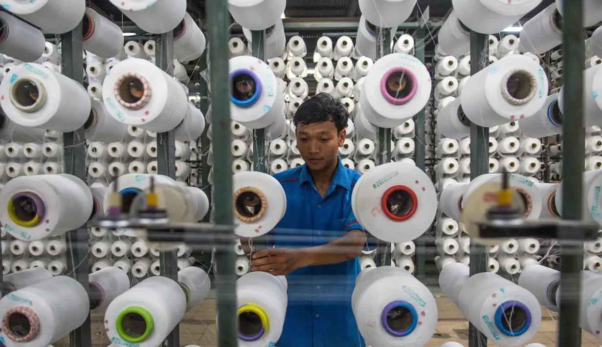 Seorang pekerja mengatur gulungan benang untuk alat tenun di pabrik Trisula Textile Industries di Cimahi, Jawa Barat pada 15 April 2025. (TIMUR MATAHARI/AFP)