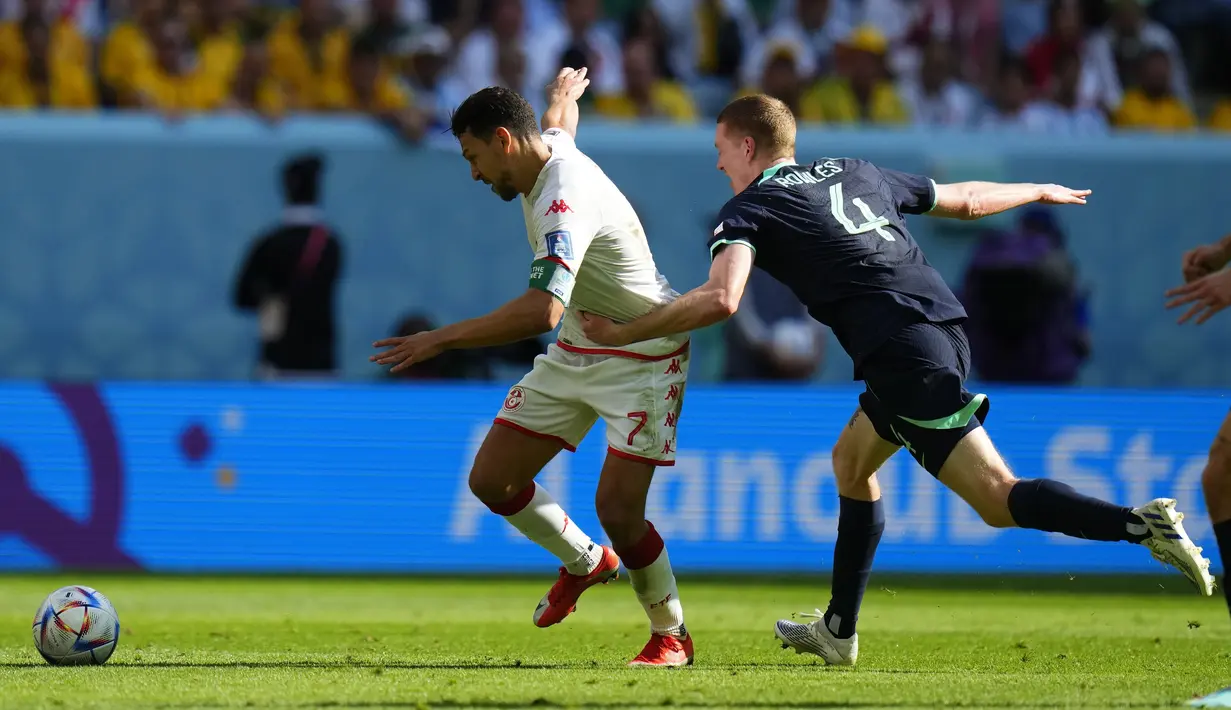 <p>Penyerang Tunisia, Youssef Msakni berusaha melewati pemain Australia, Kye Rowles selama pertandingan grup D Piala Dunia 2022 di Stadion Al Janoub di Al Wakrah, Qatar, Sabtu, 26 November 2022. Sementara Tunisia turun ke posisi ketiga dengan satu poin. (AP Photo/Petr David Josek)</p>