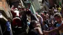 Puluhan anak-anak menyambut Santa Claus saat kunjungannya ke kawasan kumuh Petare di Caracas, Venezuela (11/12). Kunjungan Santa Claus ini untuk menghibur anak-anak dalam menyambut datangnya natal. (Reuters/Ueslei Marcelino)