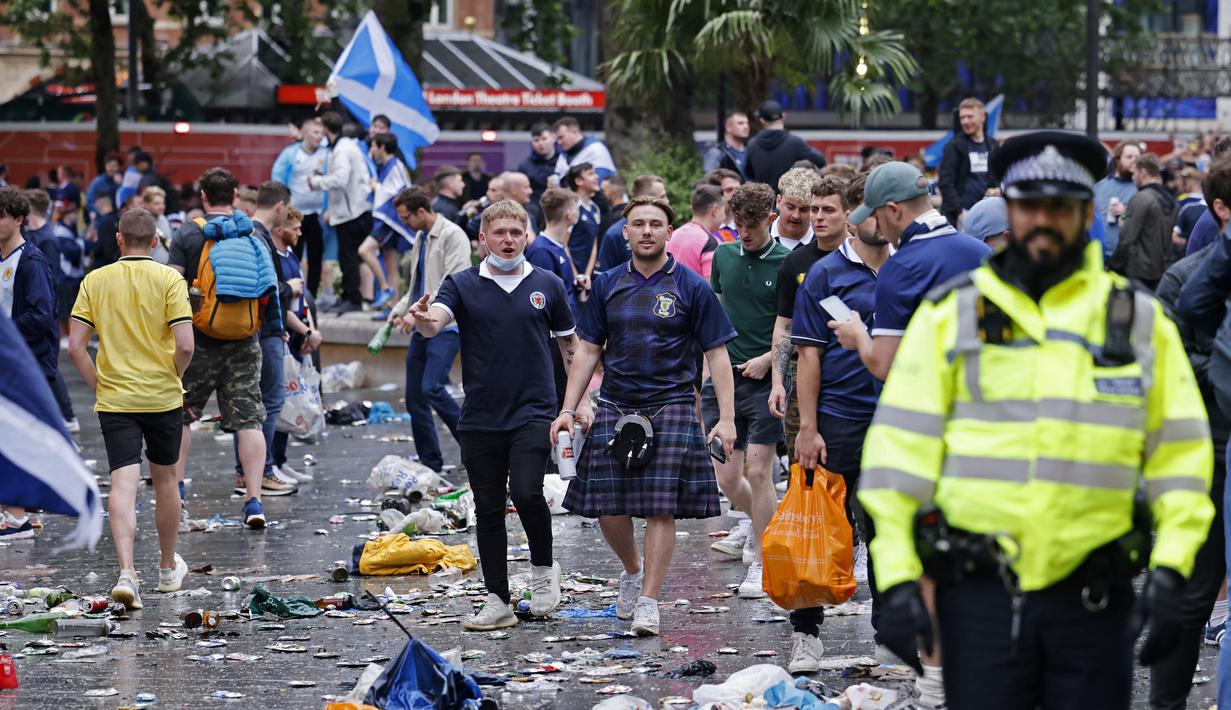 Penggemar Skotlandia berjalan di antara sampah yang ditinggalkan oleh penggemar yang berpesta sebelum pertandingan grup D kejuaraan sepak bola Euro 2020 antara Inggris dan Skotlandia, di London, Jumat (18/6/2021).  (AFP/Tolga Akmen)