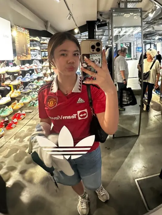 Safeea tampil mengenakan jersey MU warna merah dipadukan bawahan celana denim pendek dan sneakersnya. [@shafeeamd_]