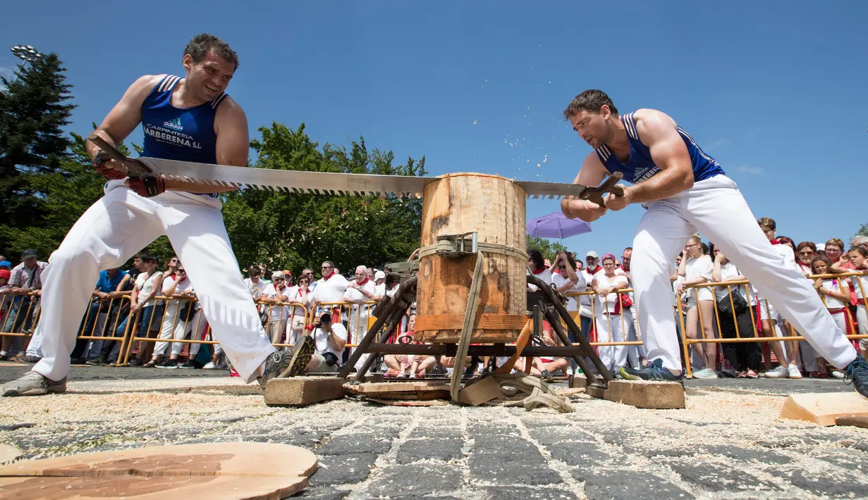 Peserta menggergaji batang pohon dengan "tronza", gergaji tradisional daerah Basque, pada hari ketiga festival San Fermin di Pamplona, Spanyol, Senin (8/7/2019). Festival San Fermin menghadirkan beberapa olahraga pedesaan Basque seperti menggergaji dan memotong pohon dengan kapak. (JAIME REINA/AFP)