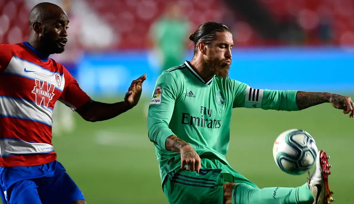 Bek Real Madrid, Sergio Ramos menendang bola dari kawalan pemain Granada, Dimitri Foulquier pada pertandingan lanjutan La Liga Spanyol di stadion Nuevo Los Carmenes di Granada (13/7/2020). Madrid menang tipis 2-1 atas Granada. (AP Photo/Jose Breton)