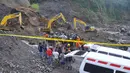 Petugas dibantu alat berat berusaha mencari korban tanah longsor di Magelang, Senin (18/12). Menurut pejabat setempat, delapan penambang tewas akibat longsor di lereng gunung berapi di pulau Jawa. (AFP Photo)