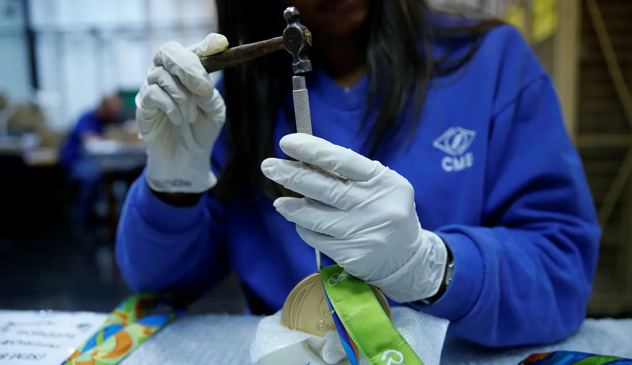 Pekerja memasangkan tali medali Olimpiade Rio 2016 di Casa da Moeda do Brasil (Brazilian Mint), Rio de Janeiro, Brasil, (28/6). Emas pada medali ini hanya sekitar 1,2 persen dan sebagain besar menggunakan plating. (REUTERS/Sergio Moraes)