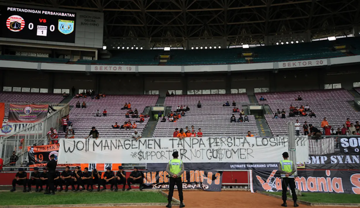 Beberapa polisi berjaga di depan salah satu spanduk protes kenaikan harga tiket saat laga Persija melawan Persela di Stadion GBK Jakarta, Minggu (1/3/2015). (Liputan6.com/Helmi Fithriansyah)