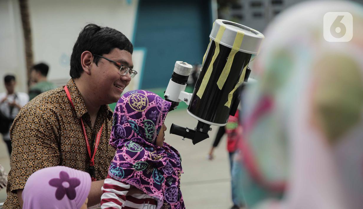 Pengunjung mengamati gerhana matahari cincin menggunakan teleskop di Planetarium Taman Ismail Marzuki, Jakarta, Kamis (26/12/2019). Planetarium menyediakan sekitar 10 teleskop dan kacamata khusus agar pengunjung bisa menyaksikan gerhana matahari cincin dengan aman. (Liputan6.com/Faizal Fanani)