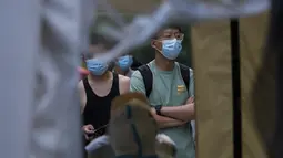 Petugas bersiap mengambil sampel tenggorokan warga di tempat pengujian COVID-19 di distrik Chaoyang di Beijing, Selasa (14/6/2022). Pihak berwenang memerintahkan pengujian massal tiga hari di antara sekitar 3,5 juta penduduknya menyusul terdeteksinya ratusan kasus virus corona COVID-19 terkait dengan klaster bar 24 jam. (AP Photo/Andy Wong)
