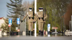 Para tentara yang mengenakan masker melakukan pertukaran sif di Makam Prajurit Tak Dikenal di Warsawa, Polandia (20/4/2020). Pemerintah Polandia telah melonggarkan beberapa kebijakan pembatasan terkait pandemi COVID-19 pada Senin (20/4). (Xinhua/Jaap Arriens)