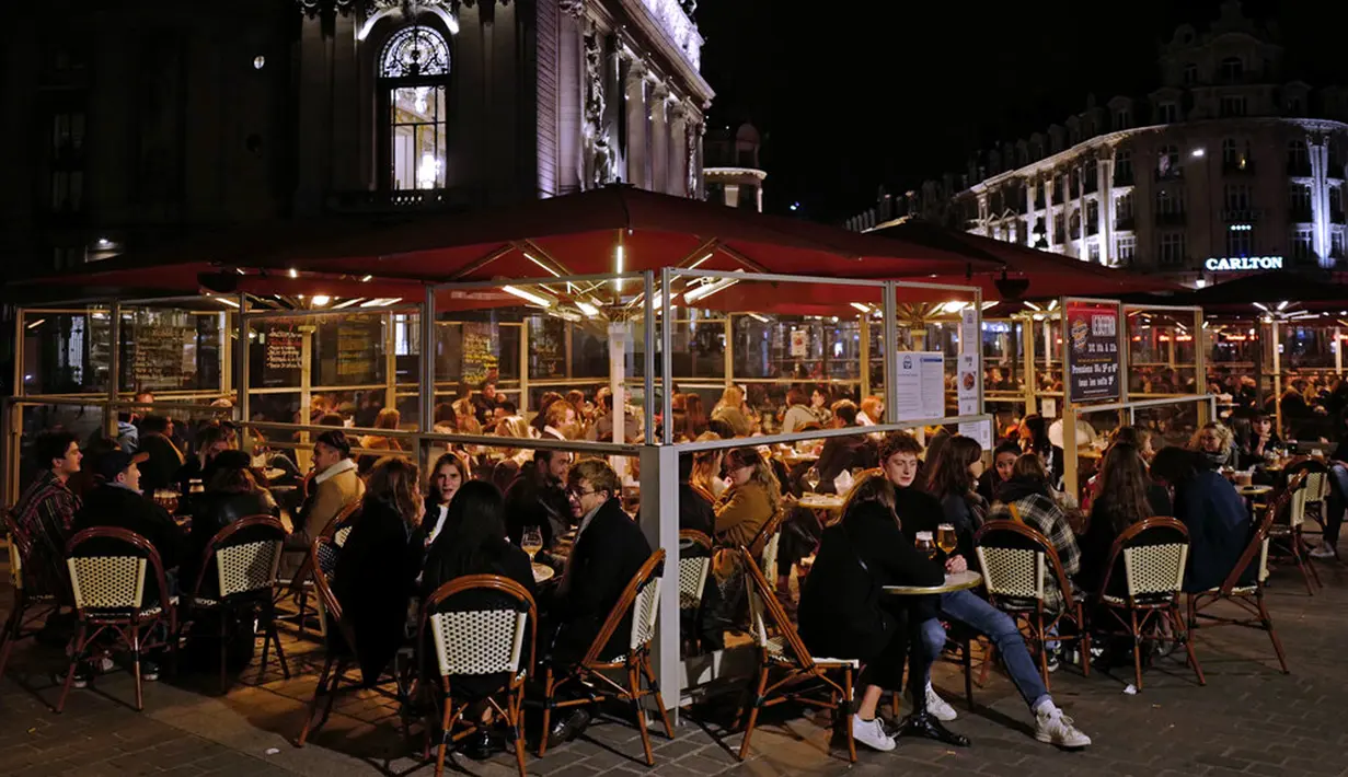 Orang-orang menikmati minuman di teras restoran di Lille, Prancis, Jumat (16/10/2020). Prancis mengerahkan 12.000 polisi untuk memberlakukan jam malam baru mulai Jumat malam hingga bulan depan untuk memperlambat penyebaran COVID-19. (AP Photo/Michel Spingler)