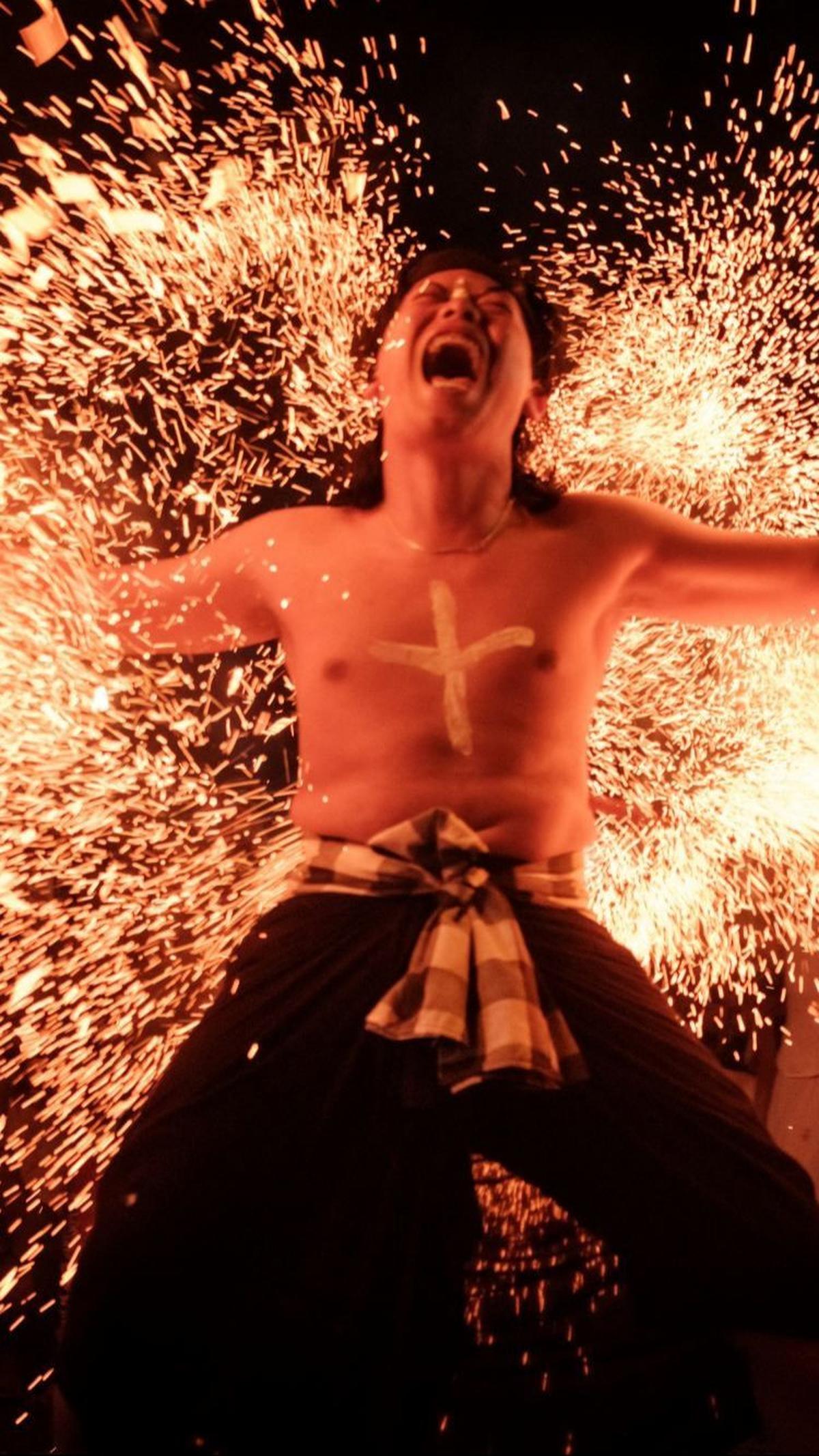 Reaksi salah satu pria Hindu saat menahan pukulan daun kelapa yang membara. Foto: Yasuyoshi CHIBA / AFP