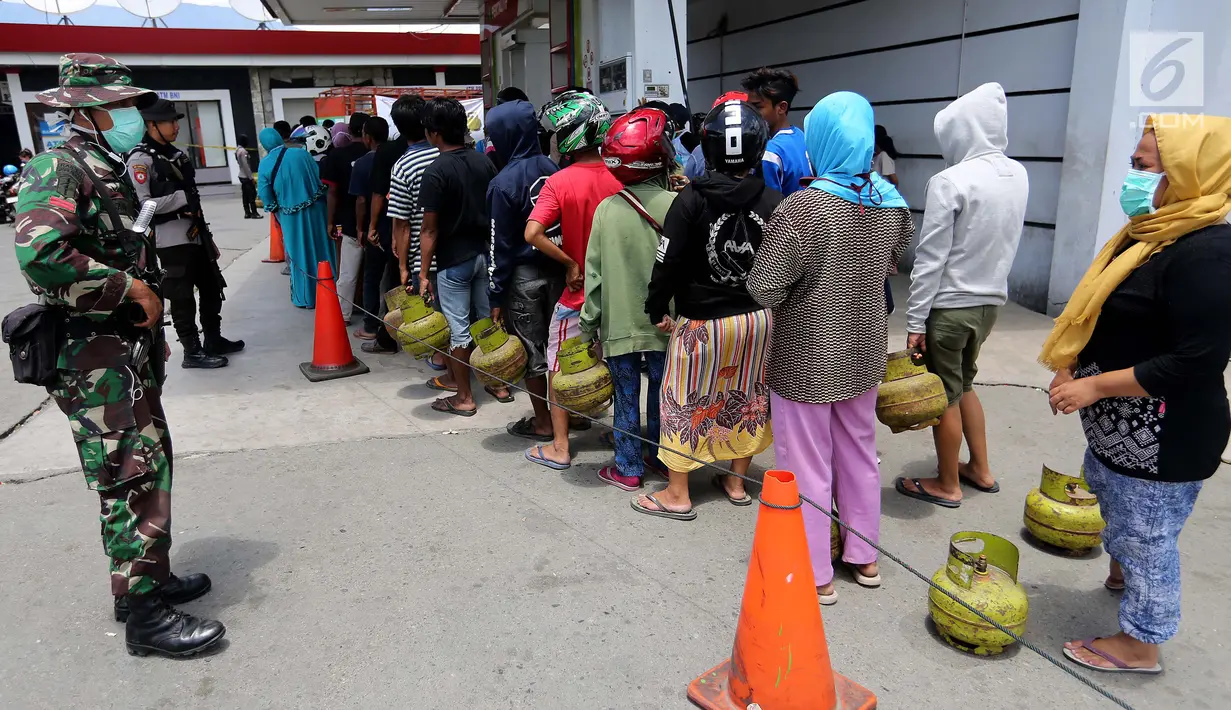 Aparat TNI menjaga antrean operasi pasar elpiji di SPBU Ki Hajar Dewantara di Palu, Sulawesi Tengah, Senin (8/10). Pertamina melakukan operasi pasar elpiji pascagempa dan tsunami Palu di 16 titik di Palu, Donggala dan Sigi (Liputan6.com/Fery Pradolo)