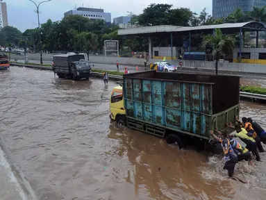 Anggota Brigif 17 Kostrad TNI AD yang kebetulan lewat bersama-sama mendorong truk yang mogok saat banjir menggenangi Jalan Tol JORR di kawasan TB Simatupang, Jakarta Selatan, Sabtu (20/2/2021). Banjir terjadi akibat luapan Kali Serua yang berada di pinggir jalan tol. (merdeka.com/Arie Basuki)