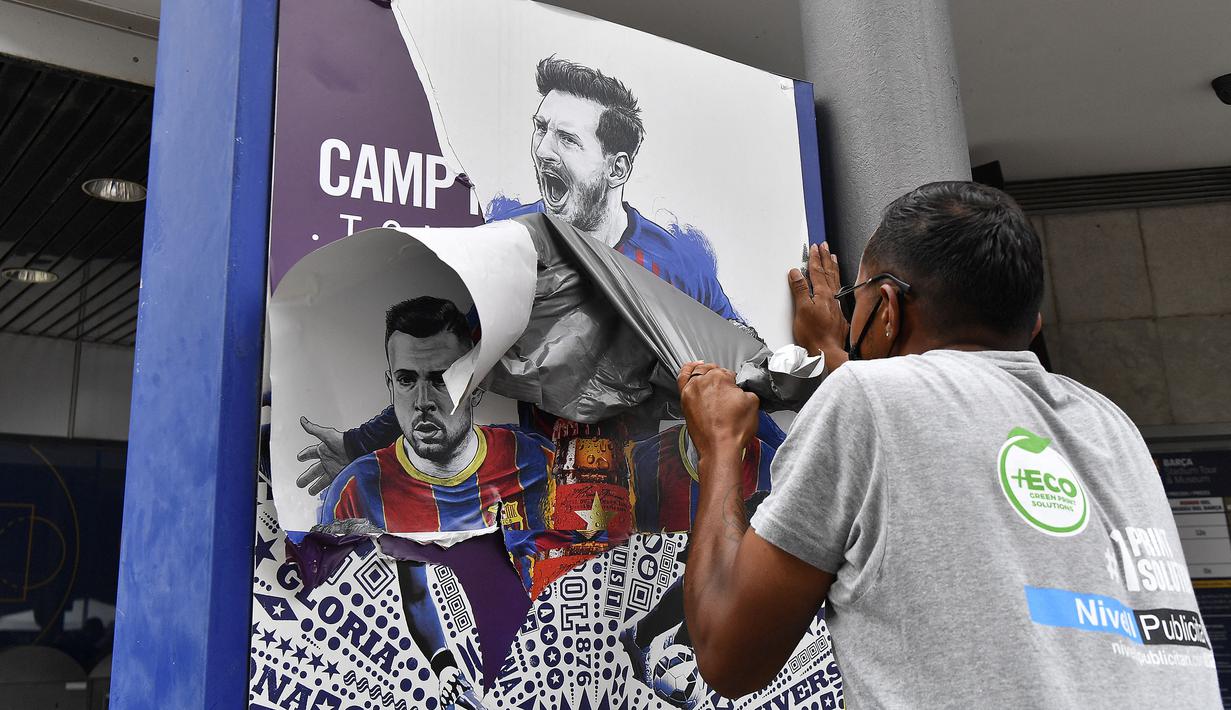 Pekerja melepas poster yang menampilkan pemain depan Argentina, Lionel Messi di pintu masuk Stadion Camp Nou, Barcelona pada Selasa, 10 Agustus 2021. Lionel Messi resmi meninggalkan Barcelona akibat masalah finansial klub dan peraturan dari Liga Spanyol. (AFP/Pau Barrena)