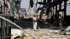 Seorang pria menggendong anaknya di sebuah bangunan pabrik pipa dan pompa air yang hancur akibat serangan udara Arab Saudi di Sanaa, Yaman, Kamis (15/9). Dalam serangan ini tidak ada korban jiwa. (REUTERS/Khaled Abdullah)