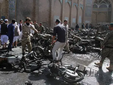 Sejumlah pria memindahkan bangkai motor yang hangus terbakar dalam ledakan bom di luar sebuah masjid bersejarah di kota Herat, Afghanistan, Selasa (6/6). Ledakan ini menyebabkan tujuh orang tewas dan 15 lainnya terluka. (AP Photos/Hamed Sarfarazi)
