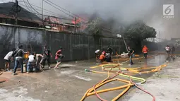 Petugas pemadam kebakaran bersana warga mencoba memadamkan api yang membakar pemukiman padat penduduk di kawasan Manggarai, Jakarta, Rabu (10/7/2019). Belum diketahui pasti penyebab api membakar pemukiman warga tersebut. (Kapanlagi.com/Budy Santoso)