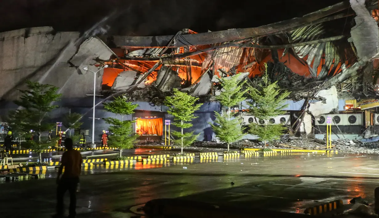Kondisi bangungan pusat perbelanjaan yang roboh dan api masih menyala saat diterjadi kebakaran di kota Davao, Filipina Selatan (23/12). (AFP Photo / Manman Dejeto)