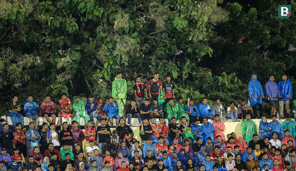 Sejumlah pendukung tuan rumah menggunakan jas hujan saat menyaksikan laga leg kedua final Pegadaian Liga 2 2023/2024 antara Semen Padang menghadapi PSBS Biak di Stadion GOR Haji Agus Salim, Padang, Sabtu (9/3/2024). (Bola.com/Bagaskara Lazuardi)