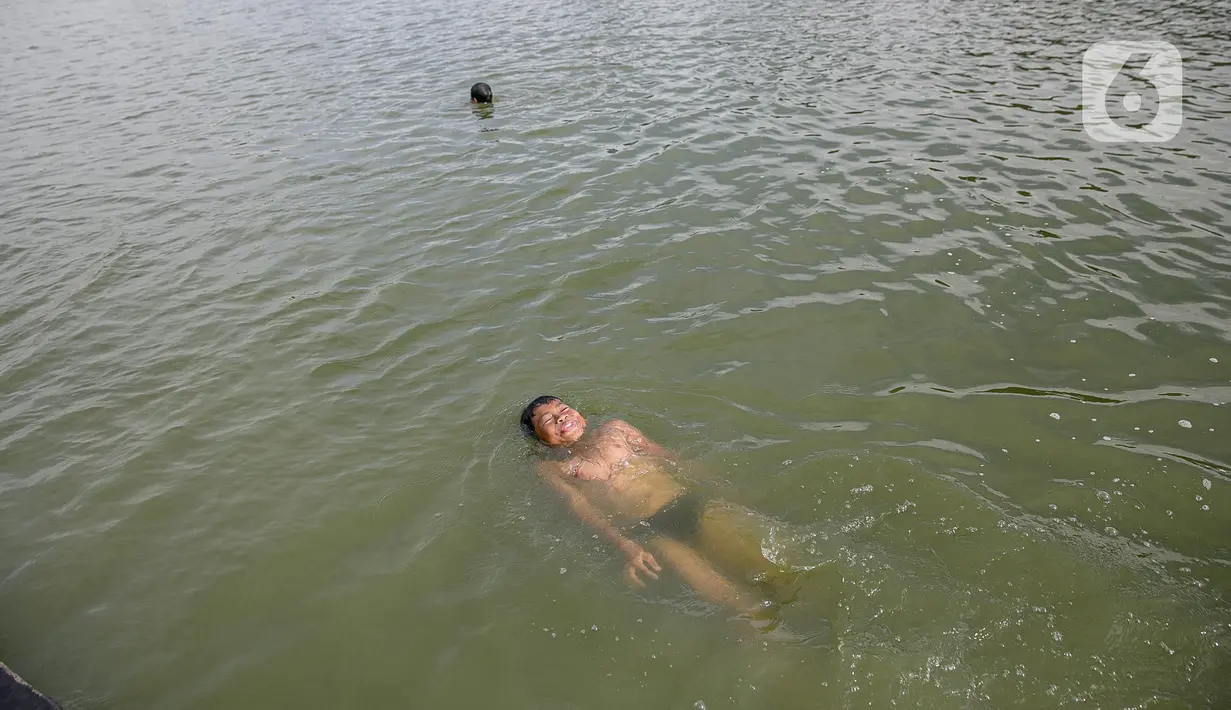 Seorang anak berenang di Danau Sunter, Jakarta, Selasa (2/2/2021). Minimnya lahan bermain anak membuat mereka memanfaatkan tempat yang tidak semestinya untuk bermain karena adanya risiko hanyut dan tenggelam bila tidak mampu untuk berenang. (Liputan6.com/Faizal Fanani)