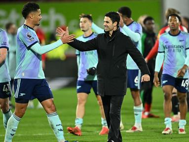 Pelatih Arsenal, Mikel Arteta (tengah) merayakan kemenangan bersama William Saliba pada akhir laga pekan 19 Premier League 2024/2025 melawan Brentford di Stadion Gtech Community, London pada Rabu 1 Januari 2025 waktu setempat atau Kamis 2 Januari 2025 dini hari WIB. (JUSTIN TALLIS/AFP)