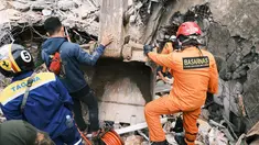 Petugas Basarnas mencari korban di reruntuhan bangunan yang rusak di Mamuju, Sulawesi Barat, Sabtu (16/1/2021). Jalan dan jembatan yang rusak, pemadaman listrik, dan kurangnya alat berat menghambat evakuasi setelah gempa bermagnitudo 6,2 SR yang melanda Majene- Mamuju. (AP Photo/ Sadly Ashari Said)