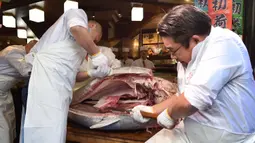 Pekerja jaringan restoran sushi ternama Sushizanmai mengiris tuna sirip biru seberat 276 kg yang dibeli perusahaannya di restoran utama mereka di Tokyo, Minggu (5/1/2020). Tuna raksasa itu dibeli dalam lelang perdana 2020 dengan harga USD 1,8 juta atau sekitar Rp 24 miliar. (Kazuhiro NOGI / AFP)