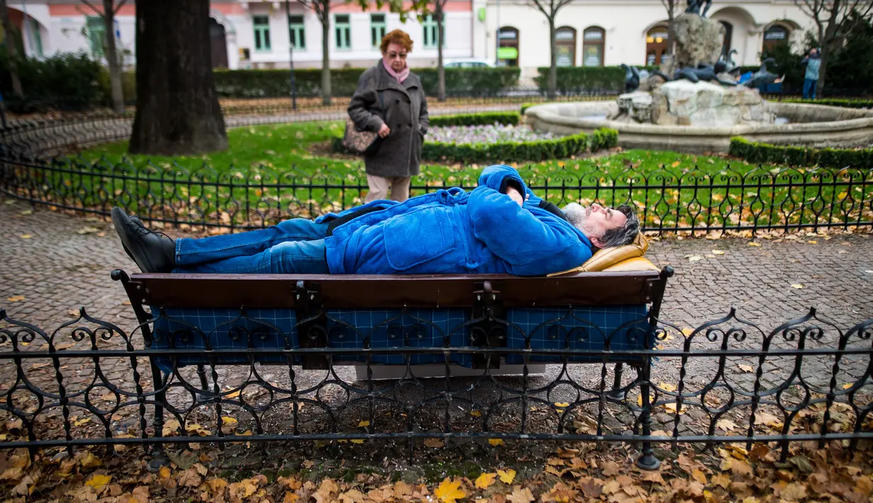 Aktivis berbaring di bangku di pusat kota Bratislava, 8 November 2018. Aksi itu untuk menunjukkan solidaritas kepada tunawisma di Hungaria yang dilarang tidur di tempat-tempat umum setelah diberlakukannya undang-undang tunawisma. (VLADIMIR SIMICEK/AFP)