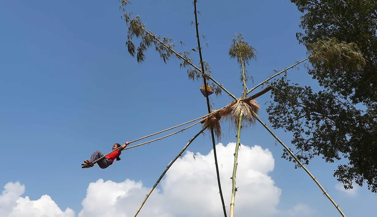 Seorang anak perempuan bermain di ayunan khas negara Nepal di Lalitpur pinggiran kota Kathmandu, Nepal (26/9). Ayunan ini dikenal sebagai 'Dashain Ping' dan dimainkan pada hari keenam festival Hindu Dashain. (AFP Photo/Prakash Mathema)