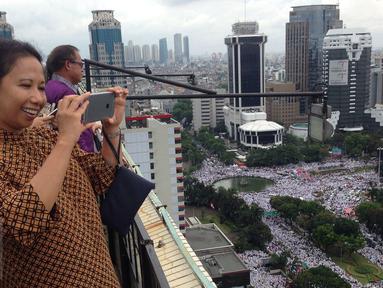 Menteri BUMN, Rini Soemarno mengabadikan gambar demo 2 Desember di atas gedung BUMN, Jakarta, Rabu (2/12). Demo 2 Desember digelar sebagai lanjutan dari aksi 4 November 2016. (Liputan6.com/Ferbian Pradolo)