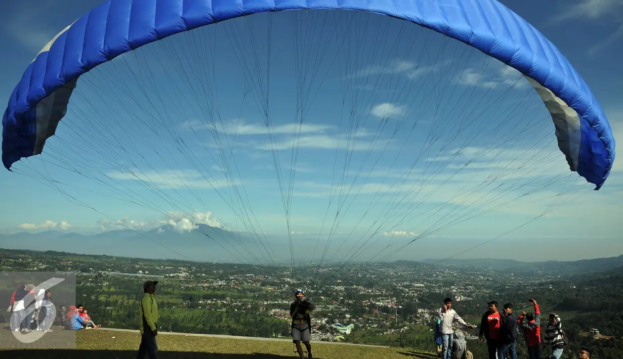 Sebuah parasut siap diterbangkan di Puncak Pass, Bogor, Jumat (6/4). Sebagian warga memanfaatkan libur panjang akhir pekan ini dengan bermain Paralayang. (Liputan6.com/Johan Tallo)