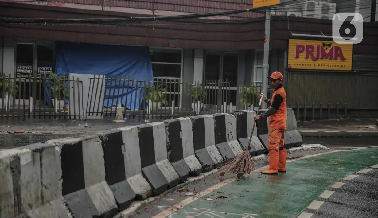 Petugas PPSU membersihkan sampah dekat beton pembatas di Jalan Senopati, Jakarta, Minggu (29/12/2019). Pascakejadian mobil tabrak Apotek Senopati, Suku Dinas Bina Marga memasangan beton pembatas untuk meminimalisir kejadian serupa terulang kembali. (Liputan6.com/Faizal Fanani)