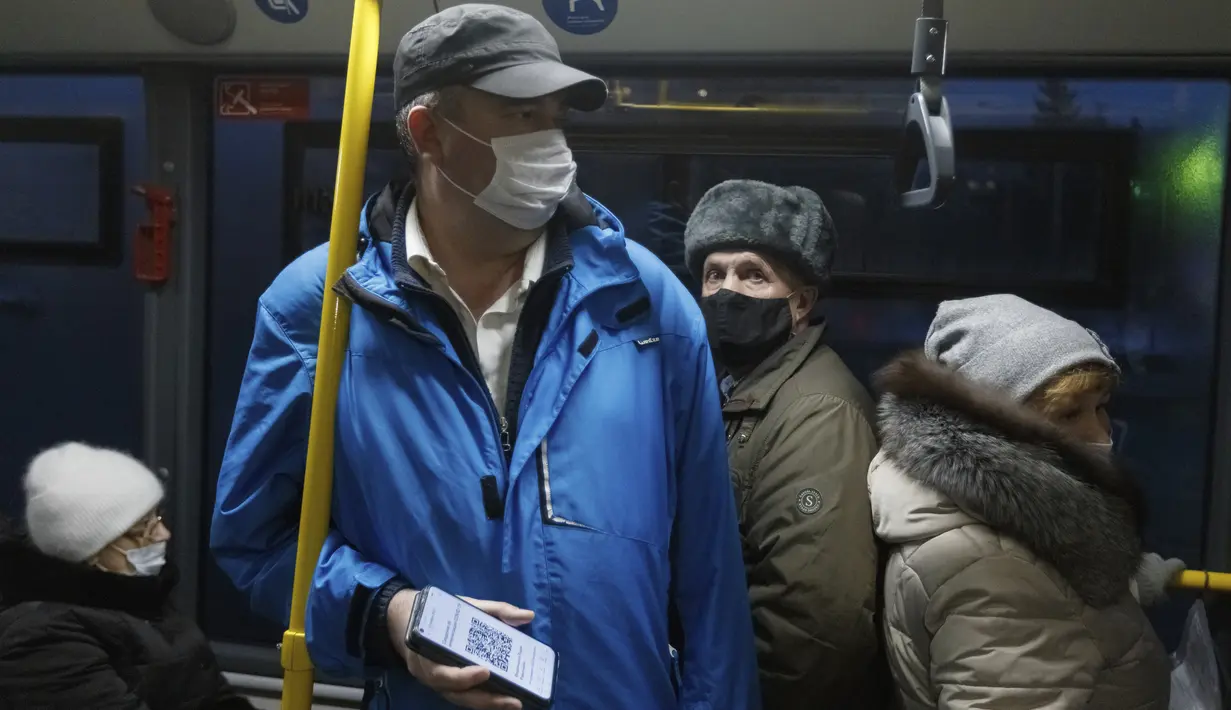 Seorang penumpang yang mengenakan masker menunjukkan kode QR melalui layar ponsel pintar kepada petugas di dalam bus di Kazan, Senin (22/11/2021). Kazan, menjadi yang pertama di Rusia yang mulai mewajibkan bukti vaksinasi atau penyakit sebelumnya untuk akses transportasi umum. (AP Photo)