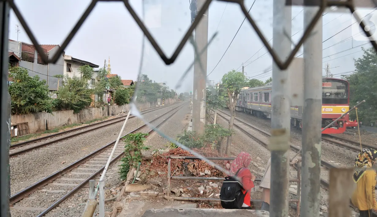 Warga menunggu kereta melintas saat hendak menyeberangi rel Stasiun Buaran lama, Jakarta, Selasa (8/10/2019). Stasiun Buaran lama yang saat ini sudah usang belum juga dilakukan pembongkaran oleh pihak terkait. (merdeka.com/Iqbal Nugroho)