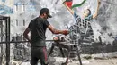 Seorang pekerja meluruskan batang baja sebagai bagian dari daur ulang bahan konstruksi yang diselamatkan dari bangunan yang hancur selama konflik Mei 2021 antara Hamas dan Israel di sepanjang jalan di Kota Gaza, Sabtu (5/6/2021). (MAHMUD HAMS/AFP)
