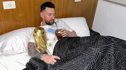 Kapten dan penyerang Argentina Lionel Messi menikmati minuman sambil memeluk trofi Piala Dunia 2022 di tempat tidur di pusat pelatihan AFA di Ezeiza, Buenos Aires, Argentina pada 20 Desember 2022. Trofi Piala Dunia merupakan satu-satunya gelar yang belum pernah diangkat pemain 35 tahun itu. Impiannya kini menjadi nyata trofi itu dipeluk sambil tidur. (Instagram/leomessi)