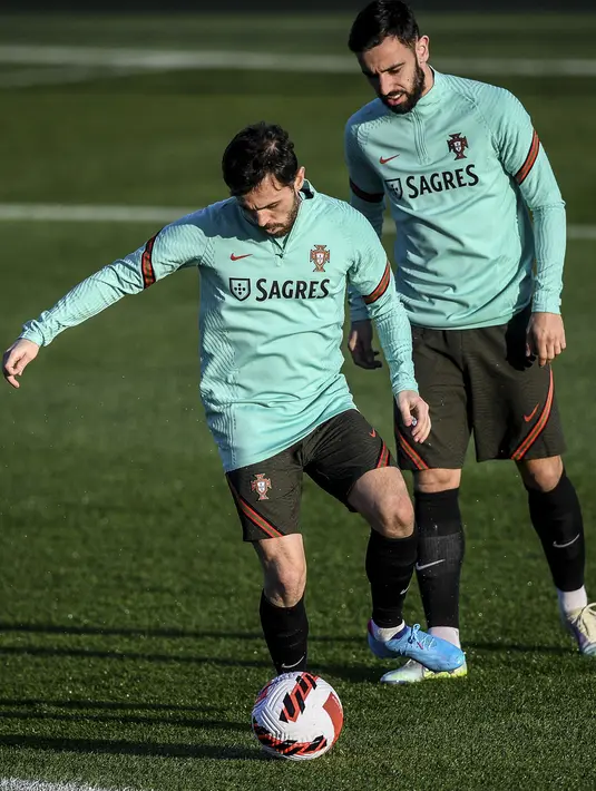 Pemain Portugal Bernardo Silva (kiri) dan Bruno Fernandes (kanan) saat sesi latihan jelang menghadapi Turki pada pertandingan sepak bola kualifikasi Piala Dunia 2022 di kamp pelatihan Cidade do Futebol, Oeiras, Portugal, 21 Maret 2022. (PATRICIA DE MELO MOREIRA/AFP)