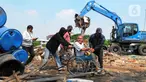 Warga melintas dekat alat berat saat menghancurkan bangunan yang terdampak proyek sodetan Ciliwung menuju Kanal Banjir Timur (KBT) di Kelurahan Cipinang Besar Selatan, Jakarta, Kamis (12/1/2023). Warga ber-KTP DKI Jakarta akan direlokasi ke rumah susun Cipinang Besar Utara, sedangkan para pedagang akan ditempatkan di pasar PD Pasar Jaya. (merdeka.com/Imam Buhori)