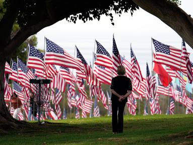 Seorang pengunjung melihat bendera Amerika Serikat (AS) untuk memperingati serangan teroris 11 September di halaman Universitas Pepperdine, Malibu, California, AS, Senin (11/9/2023). AS mengenang 22 tahun tragedi kelam serangan 11 September (9/11) di menara kembar World Trade Center (WTC), yang menewaskan nyaris 3.000 orang pada 2001. (AP Photo/Marcio Jose Sanchez)