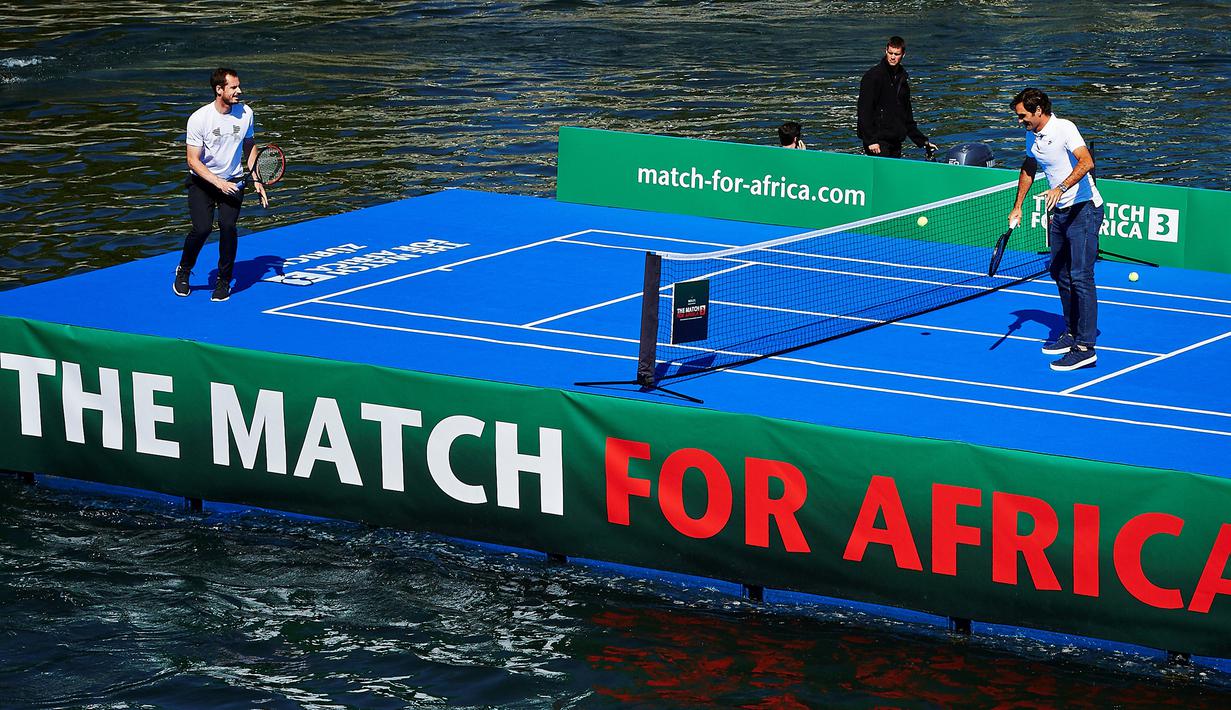 Petenis Roger Federer mengembalikan bola ke arah petenis Andy Murray pada pertandingan amal di sebuah lapangan kecil di atas sungai Kota Zurich, Senin (10/4). Pertandingan amal itu mampu menggalang dana 2 juta euro (Rp28 miliar). (Michael Buholzer/AFP)