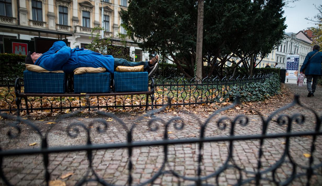 Aktivis tidur di bangku taman di pusat kota Bratislava untuk mengekspresikan solidaritas kepada tunawisma di Hungaria, 8 November 2018. Pasalnya tidur di tempat umum dilarang setelah undang-undang tunawisma diadopsi oleh pemerintah. (VLADIMIR SIMICEK/AFP)