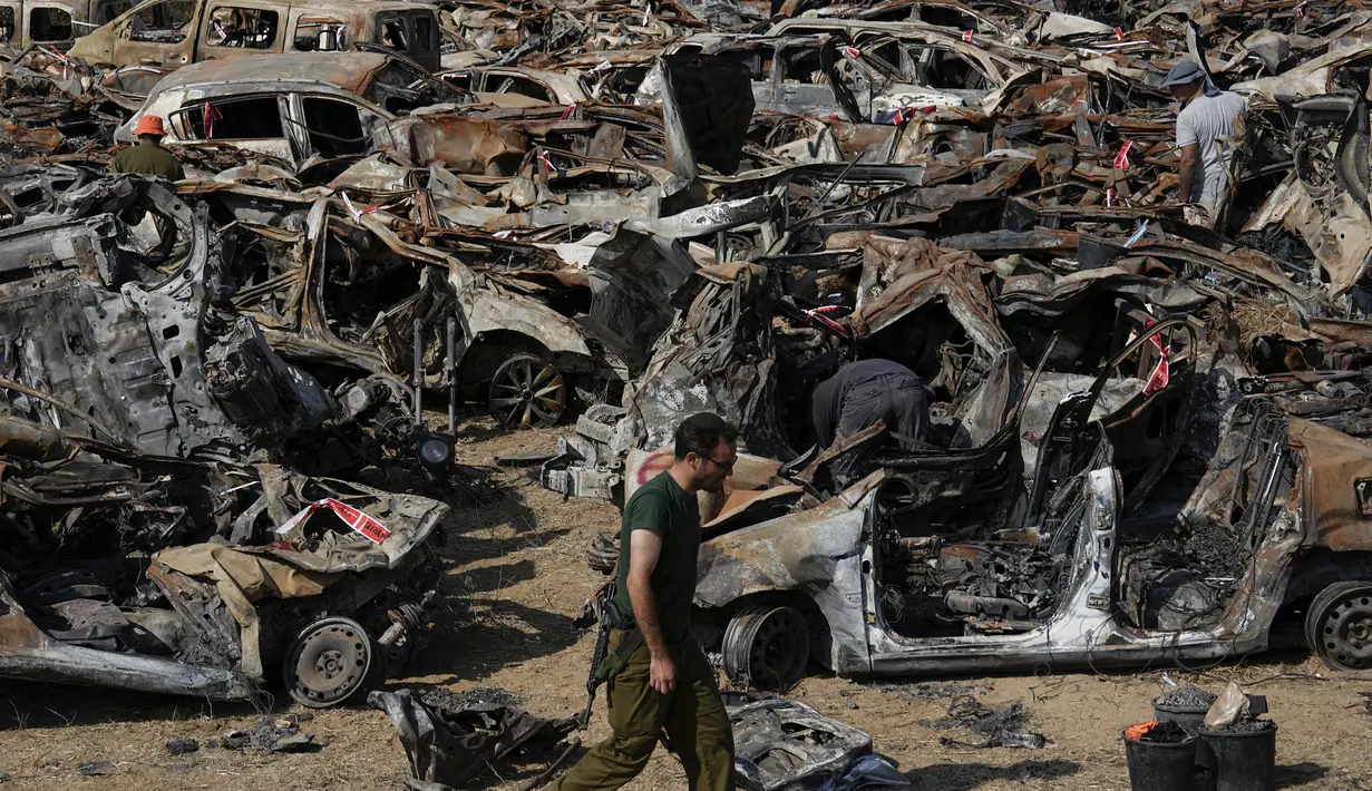 Pasukan keamanan Israel memeriksa kendaraan hangus yang terbakar dalam serangan berdarah lintas perbatasan pada 7 Oktober oleh militan Hamas, di luar kota Netivot, Israel selatan, Rabu (1/11/2023). (AP Photo/Ariel Schalit)